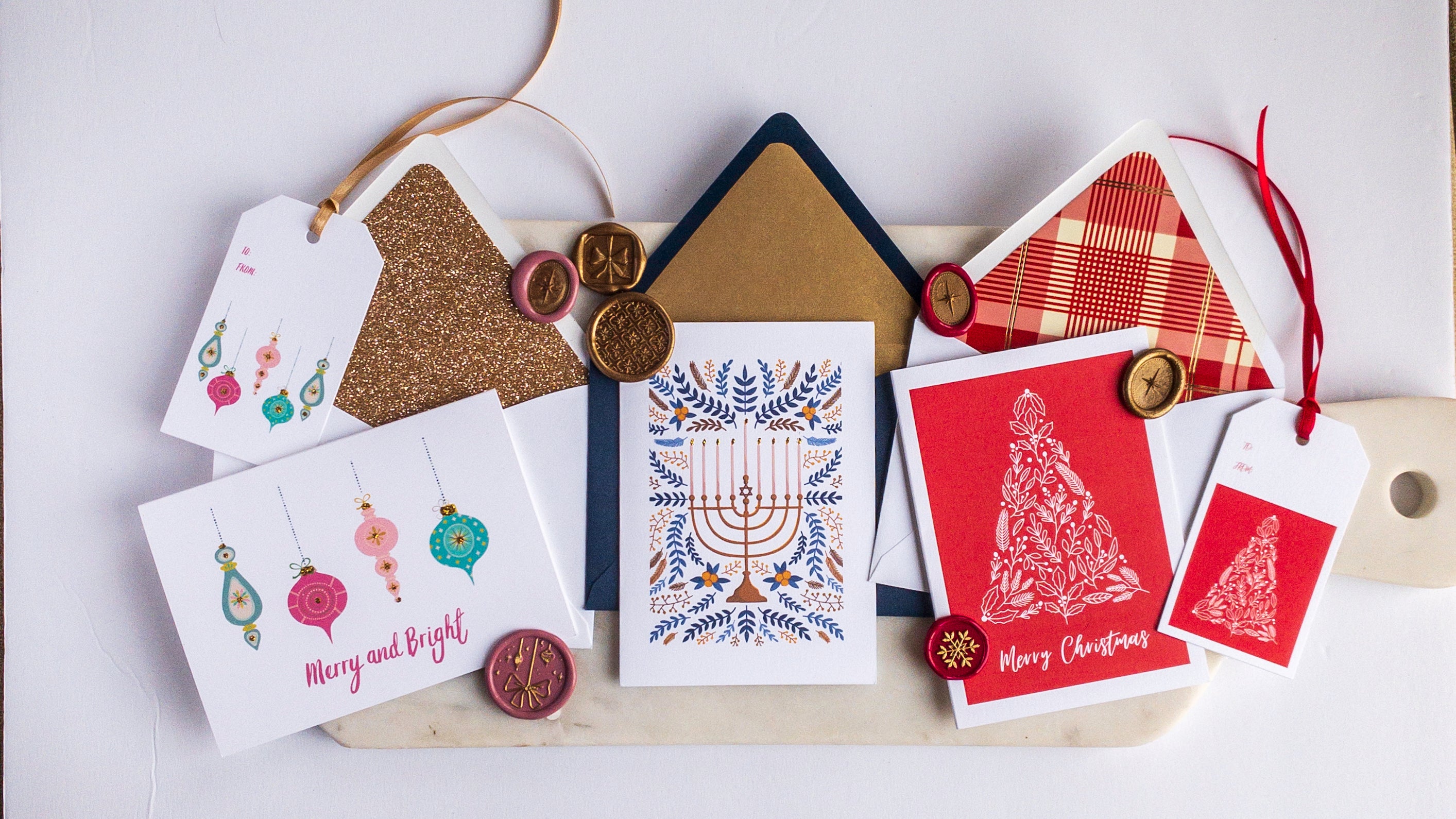 Holiday notecard sets with ornaments, menorah, and tree designs, paired with lined envelopes and wax seals